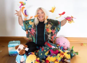 Dar Karen Treisman sitting with her books and toys, throwing feathers in the air